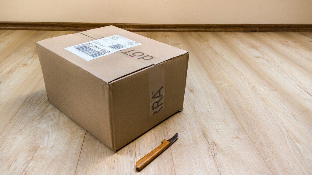 Cardboard Box on a wooden floor with a small opener.  Starting a Dropship Business. 1 Hack to Protect Your Finances in the Next Crisis.