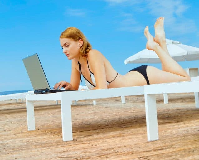 Bikini wearing young woman lying on a bench  with the beach in the background. Do the Benefits of Being an Online Solo Entrepreneur Match the Reality and also used in the article Is freelance writing overrated 