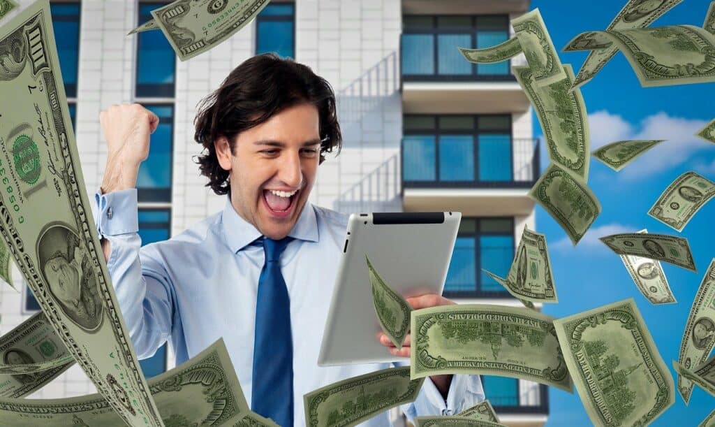Money falling from the sky around a well dressed guy pumping the air, and holding a tablet. Used in the article Is Affiliate Marketing Dead. 7 Things you Must Know for Success