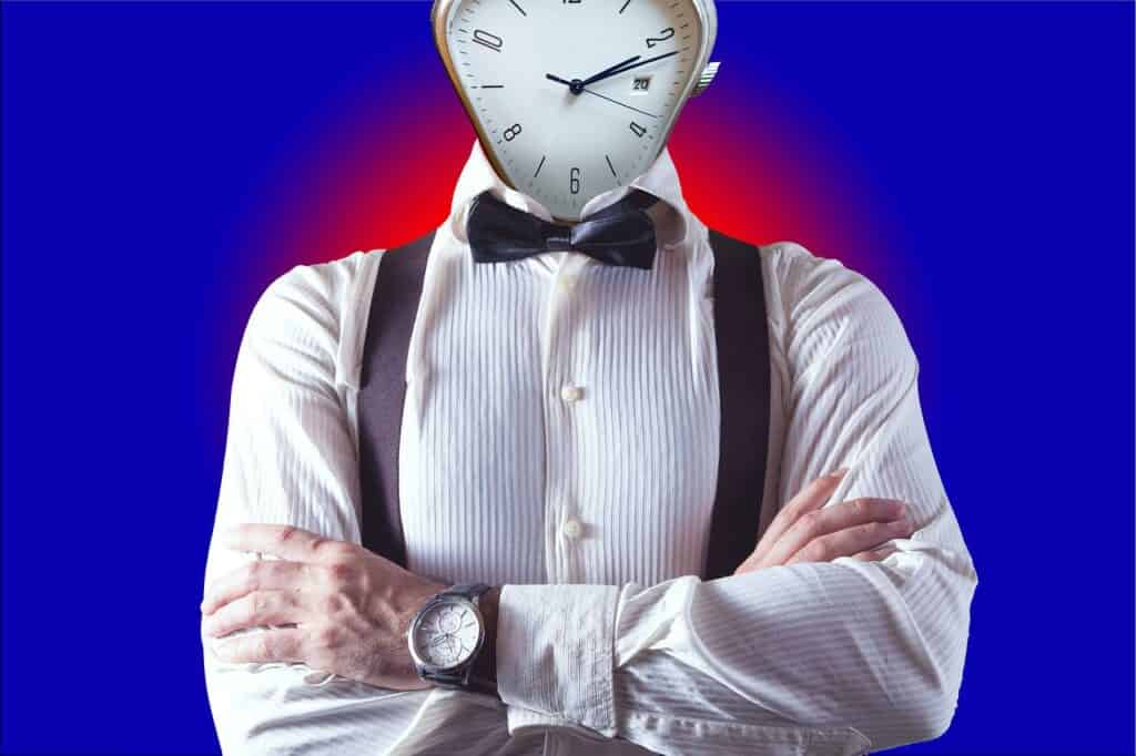 A guy with a clock face in a white shirt, with a bow tie and arms folded. A blue background with a duo tone red circle behind his shoulders, used in the article IAP College Certificate Course Review