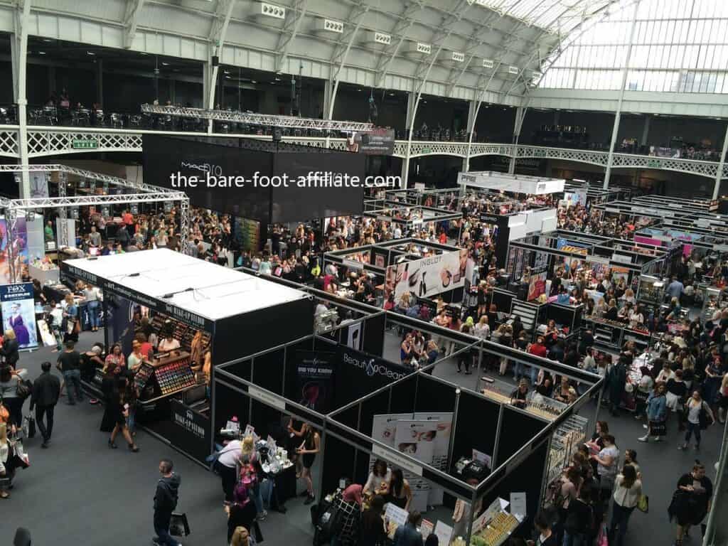 A photo of a trade show in London, with the bare foot affiliate ,com in white across a black background used in the article, Is There a Demand for Event Planners