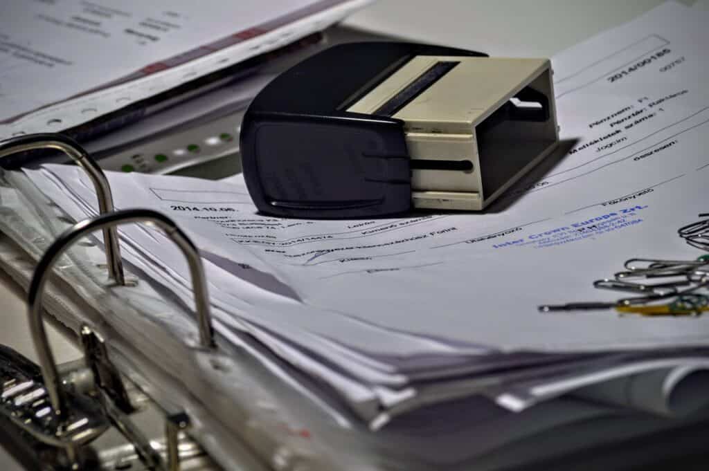 A folder with paperwork with an ink stamp resting on the top page and some paperclips in the bottom right corner. Used in the article Is Freelance Bookkeeping profitable. 