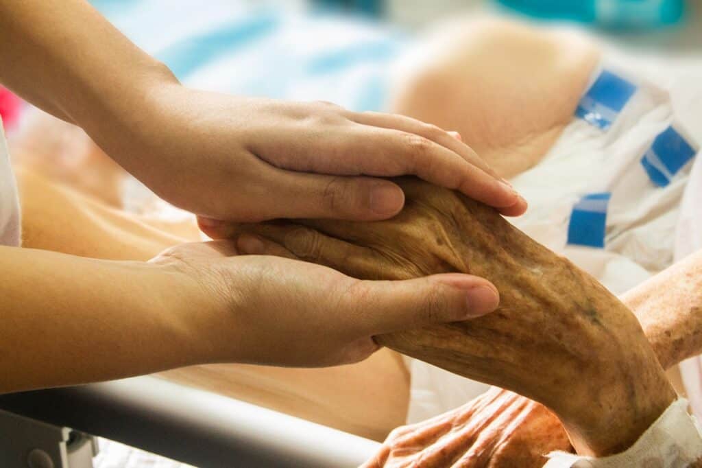 Two hands of a nurse holding an elderly patient's hand. Used in the article Is there a demand for Death Doulas?
