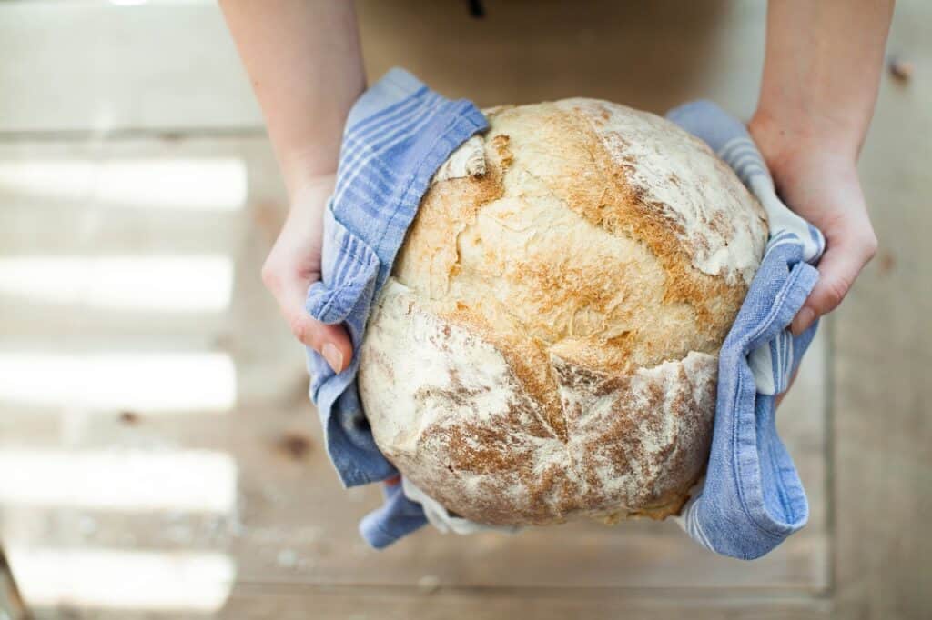 A pair of hands holding a fresh loaf of bread. Used in the article The 5 Biggest Problems Faced by Bakeries.